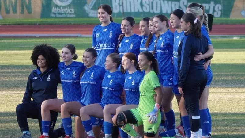 The Sydney Olympic FC U18 Girls team lined up on the pitch before a match in their blue home kit sponsored by Greenwood Finance.